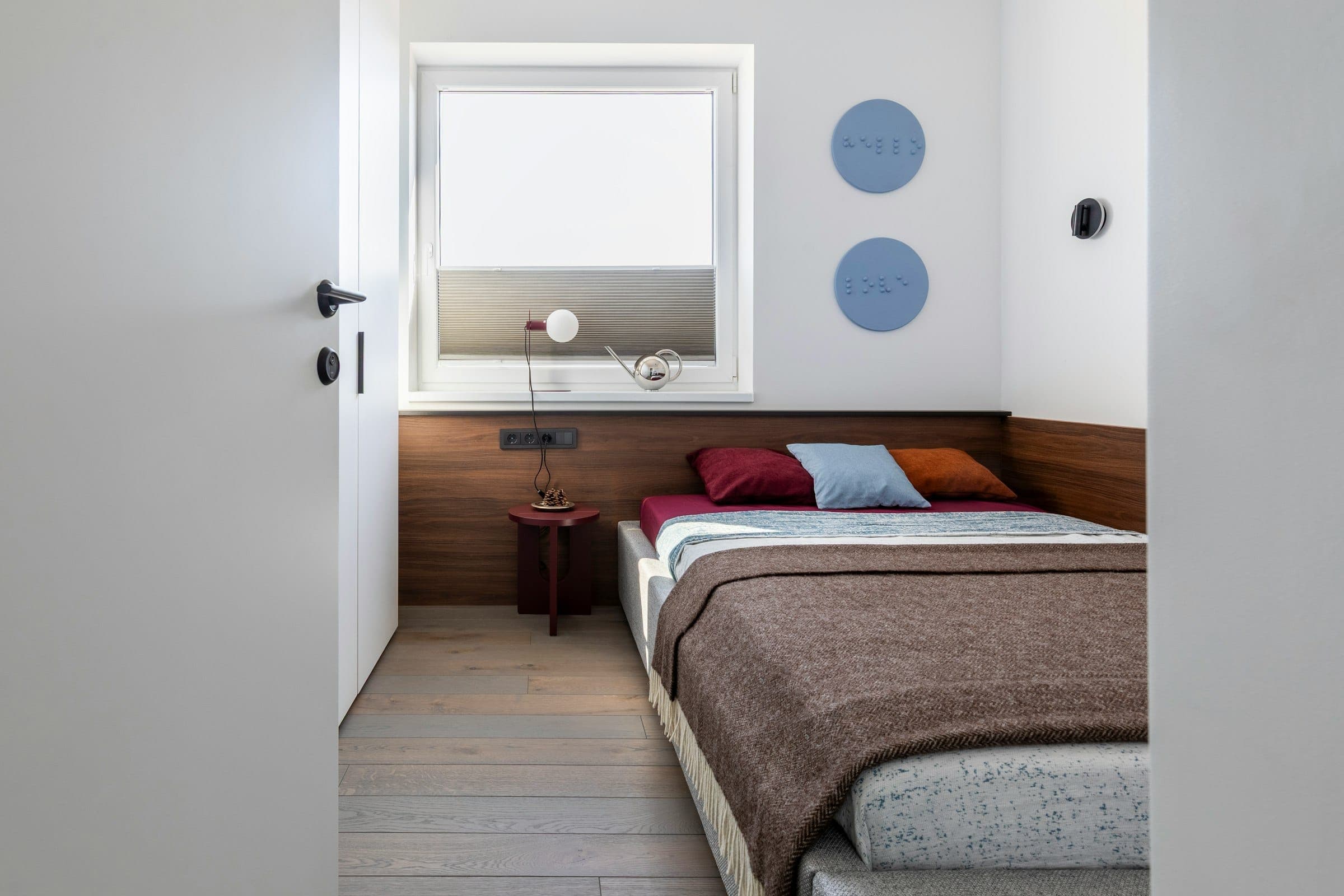 A bright single room with a made bed, a wardrobe and a window